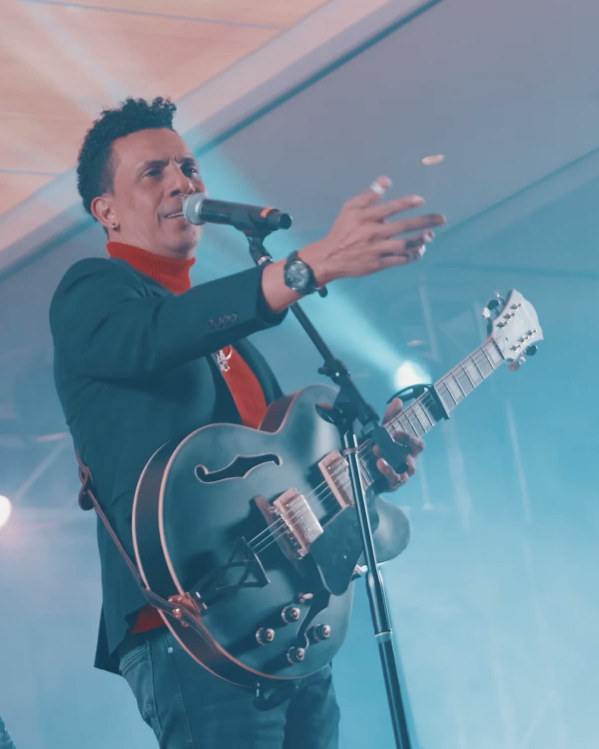 Un cantante con guitarra cantando bajo luz azul